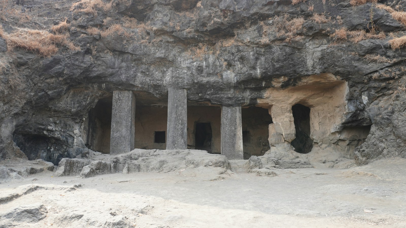 Rock-cut cave entrance with stone columns and uneven ground at Elephanta