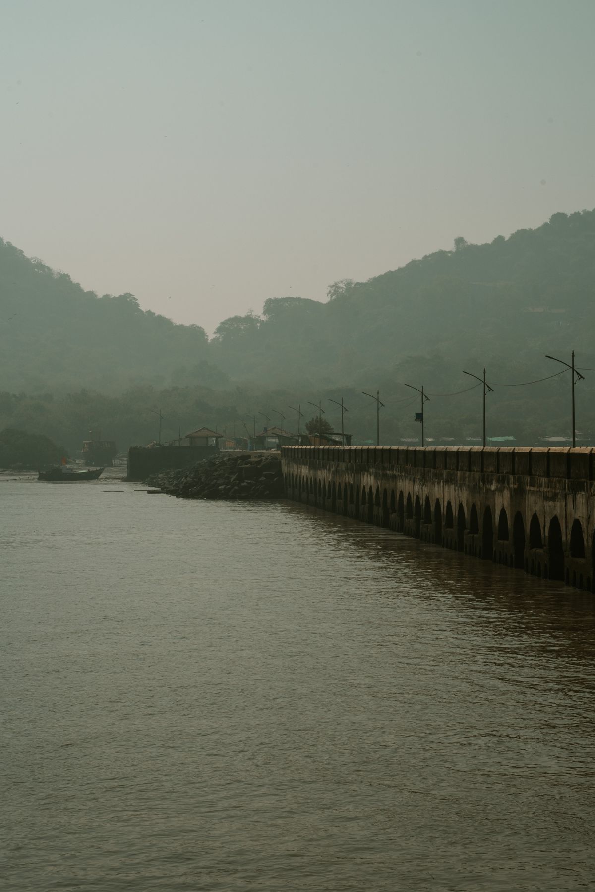 Long jetty leading towards Elephanta Island through hazy light, viewed from the water