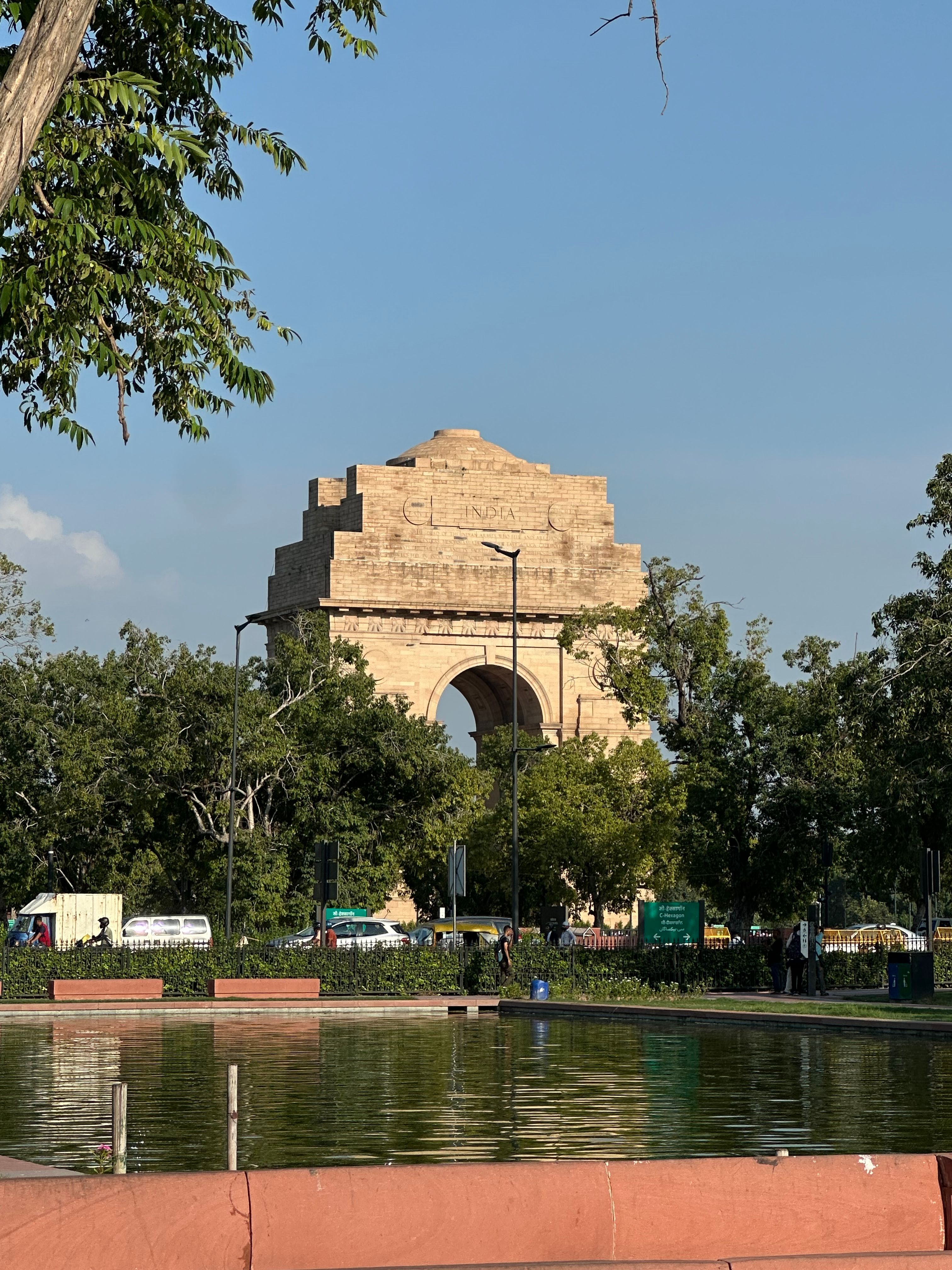 India Gate in New Delhi reflected in a pool beside green lawns