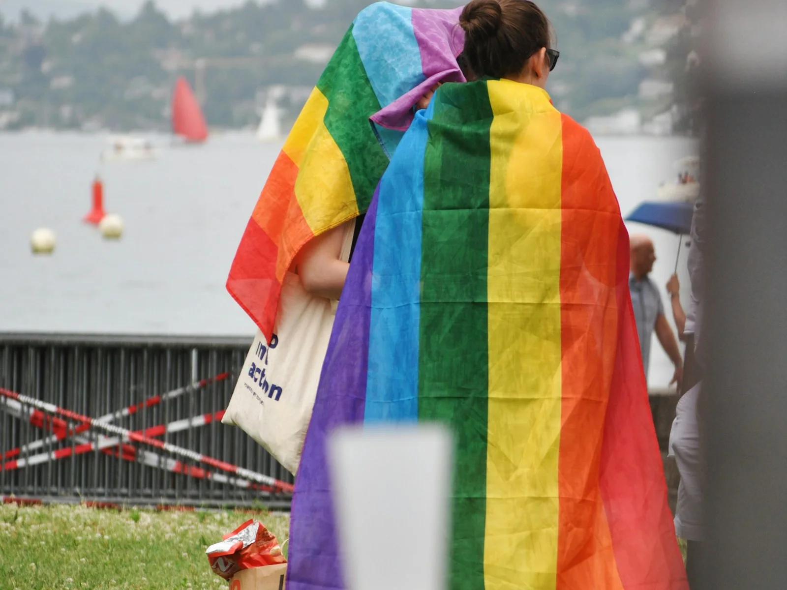 People gathering beneath a rainbow flag in the rain