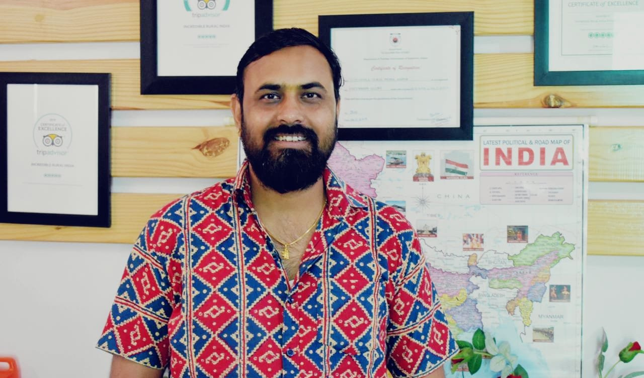 Rajendra Sharma in his travel office beside a map of India