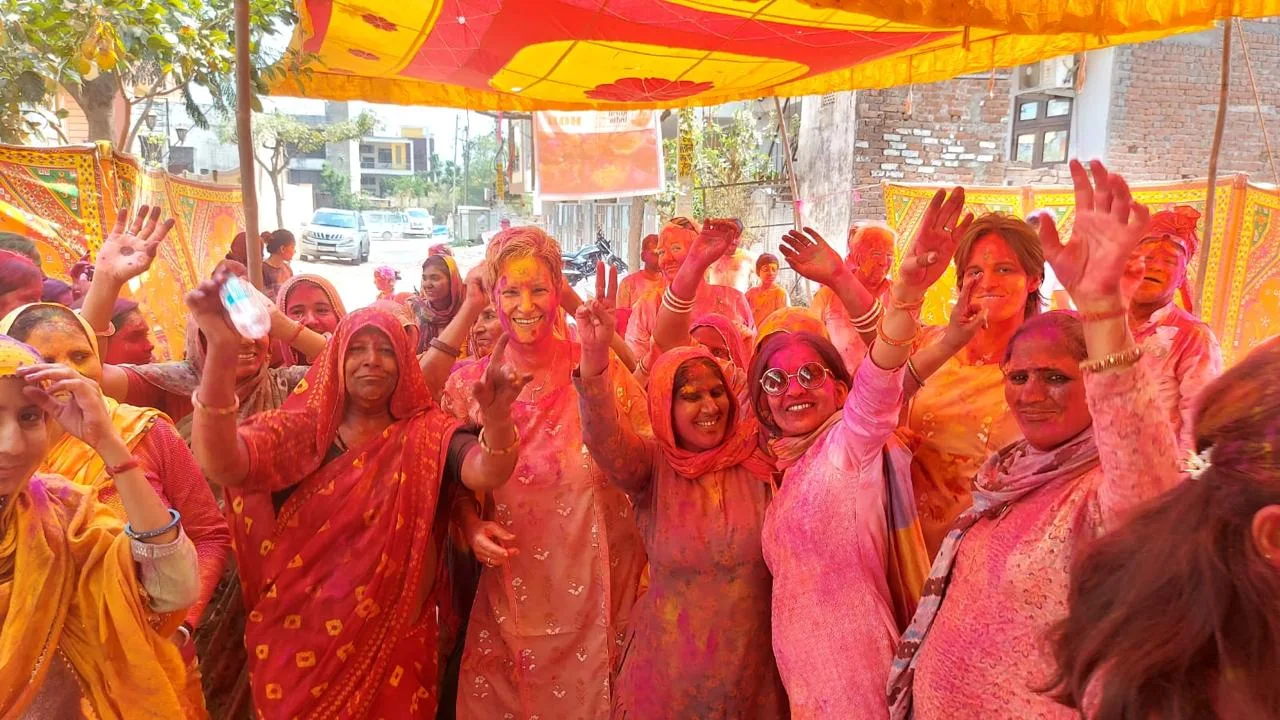 A group celebrating Holi beneath a colourful canopy