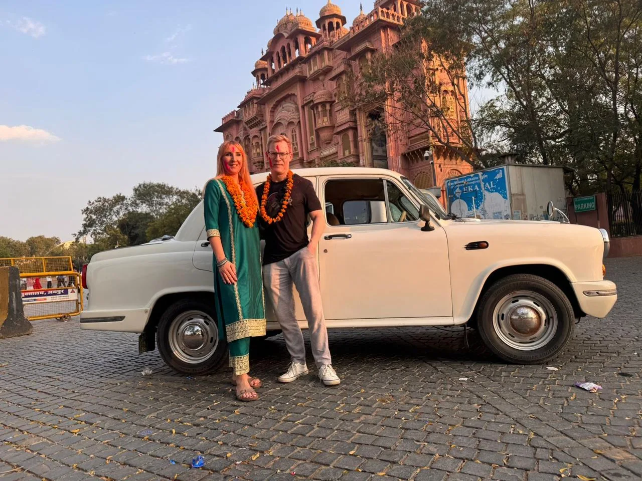 Travelers beside a white Ambassador in Jaipur