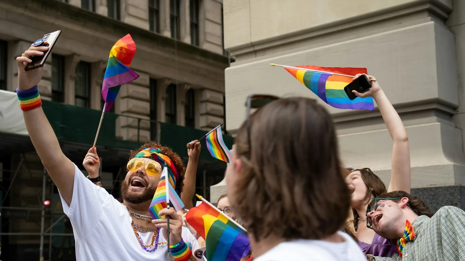 LGBTQ+ friends celebrating together with rainbow flags